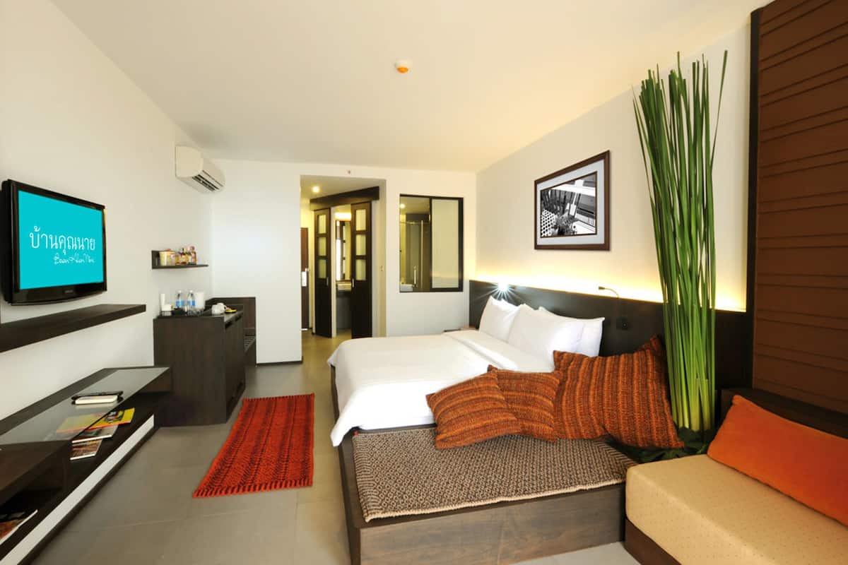 Una habitación de hotel con cama, televisión, escritorio y una planta grande.