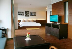 Une chambre d’hôtel avec un lit, une télévision, un bureau et une petite table sur laquelle se trouve un vase.