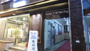 The entrance of a hotel with a glass facade, a red carpet, and signage in Korean. - Hotel Irene City (Seoul)