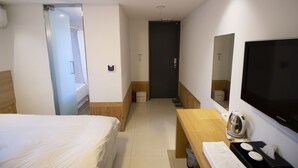 A hotel room with a bed, a desk with a kettle, a TV, and a mirror. - Hotel Irene City (Seoul)