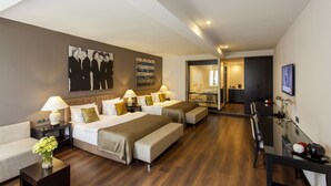 A hotel room with two beds, a sofa, a dining table, and a TV. - Quentin Boutique Hotel (Berlin)