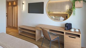 A modern bedroom with a wooden desk, a round mirror, a bed, and a small plant.