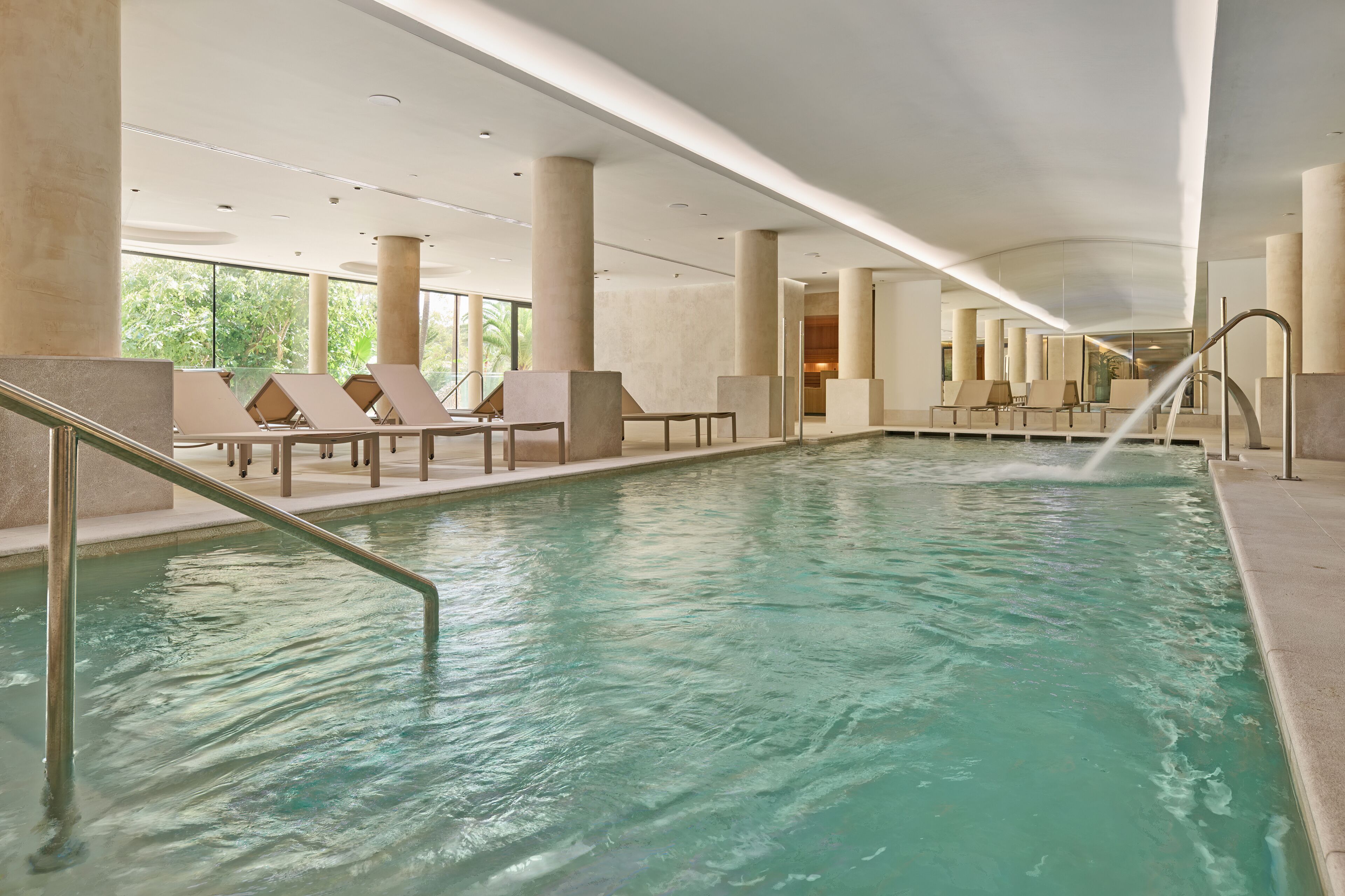 Une piscine intérieure dotée de chaises longues et offrant une vue dégagée sur l’extérieur.