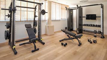 A gym with weightlifting equipment, benches, and dumbbells.