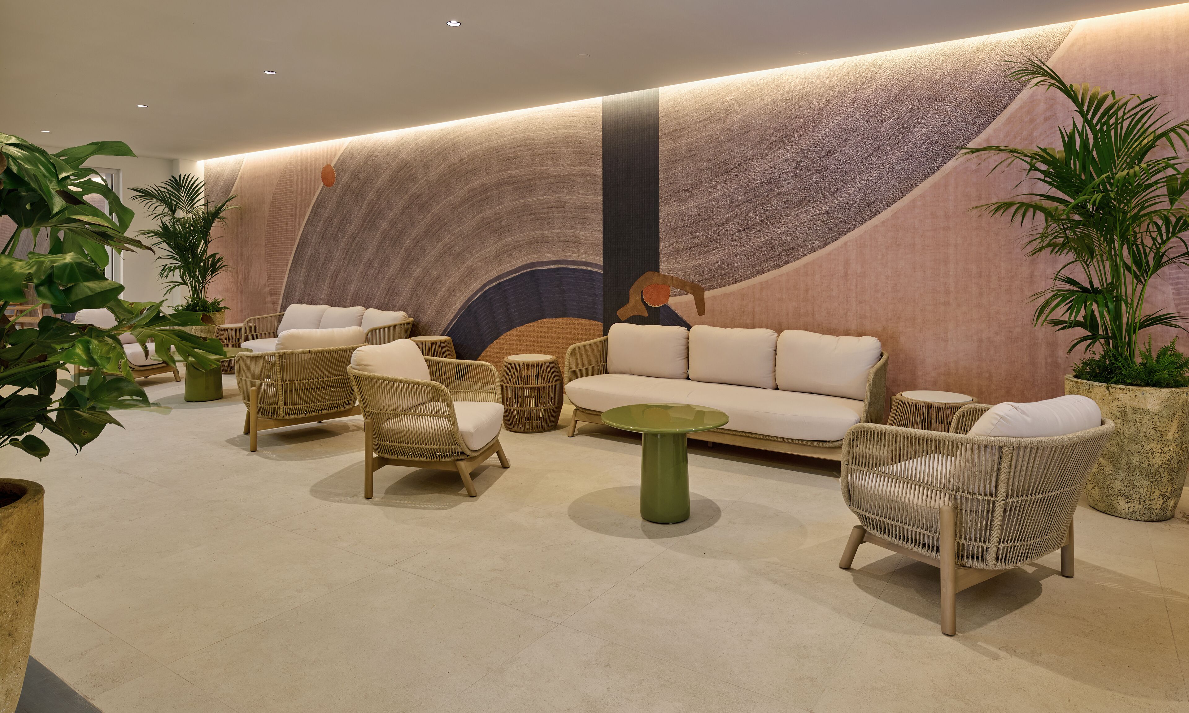 Un área de descanso moderna con muebles de mimbre, un sofá y mesas redondas.