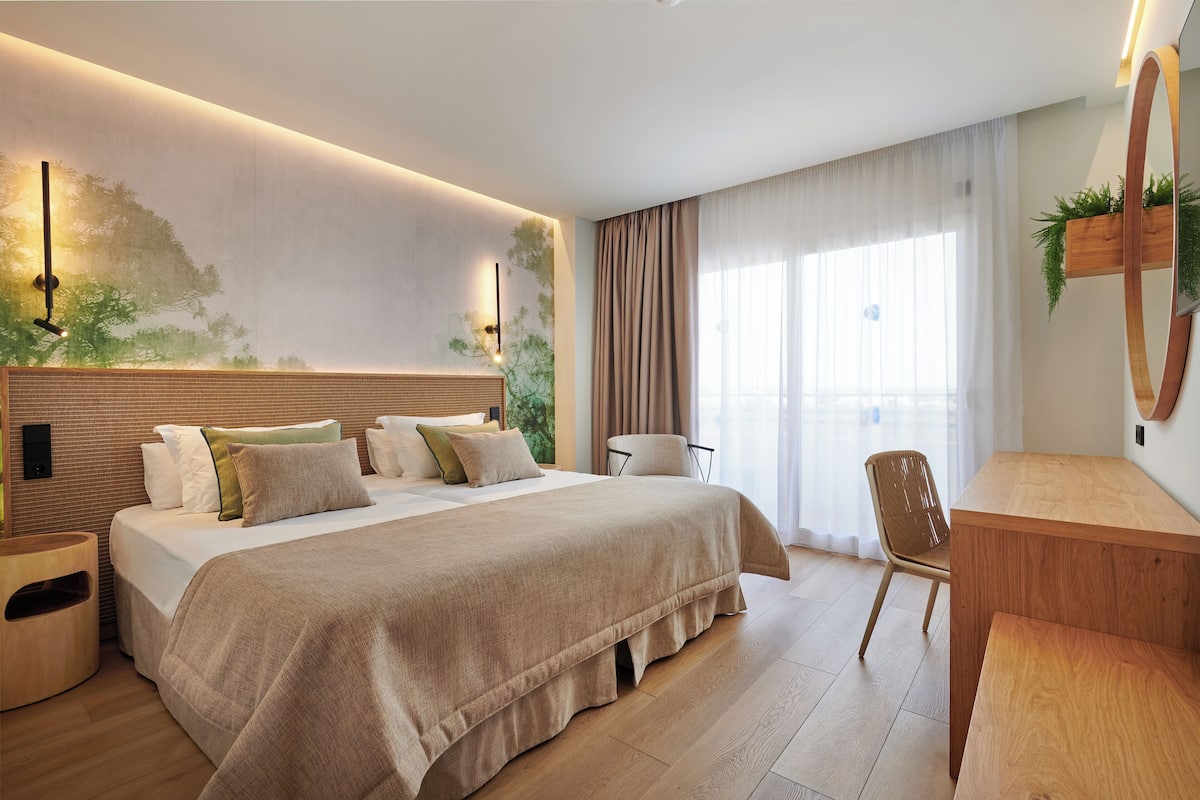 Een moderne slaapkamer met een groot bed, een houten bureau en een stoel.