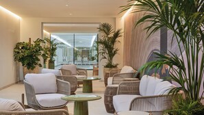 Un área de descanso moderna con muebles de mimbre y plantas en macetas grandes.