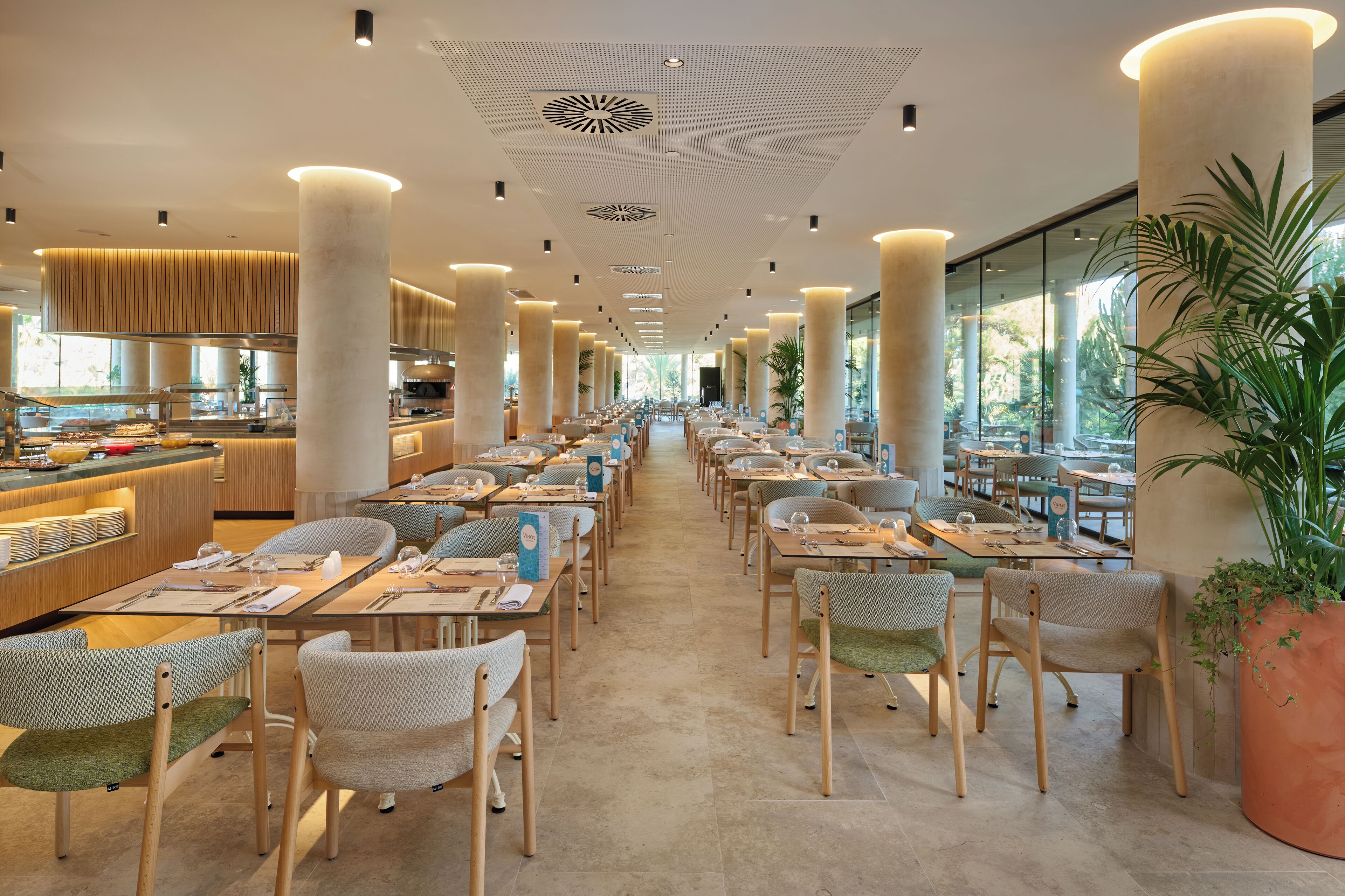 Un restaurante espacioso con techos altos, ventanas amplias y una zona de servicio central.