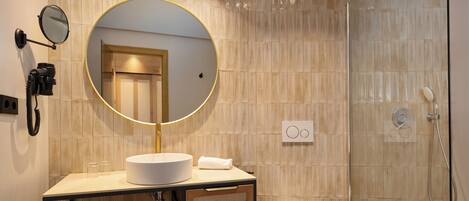 Une salle de bain moderne avec un miroir rond, un lavabo, des toilettes et une douche à parois de verre.