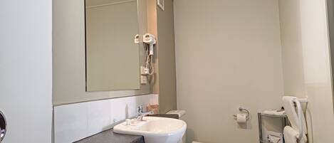 Ein Badezimmer mit Waschbecken, Spiegel, Toilette und Handtuchhalter.