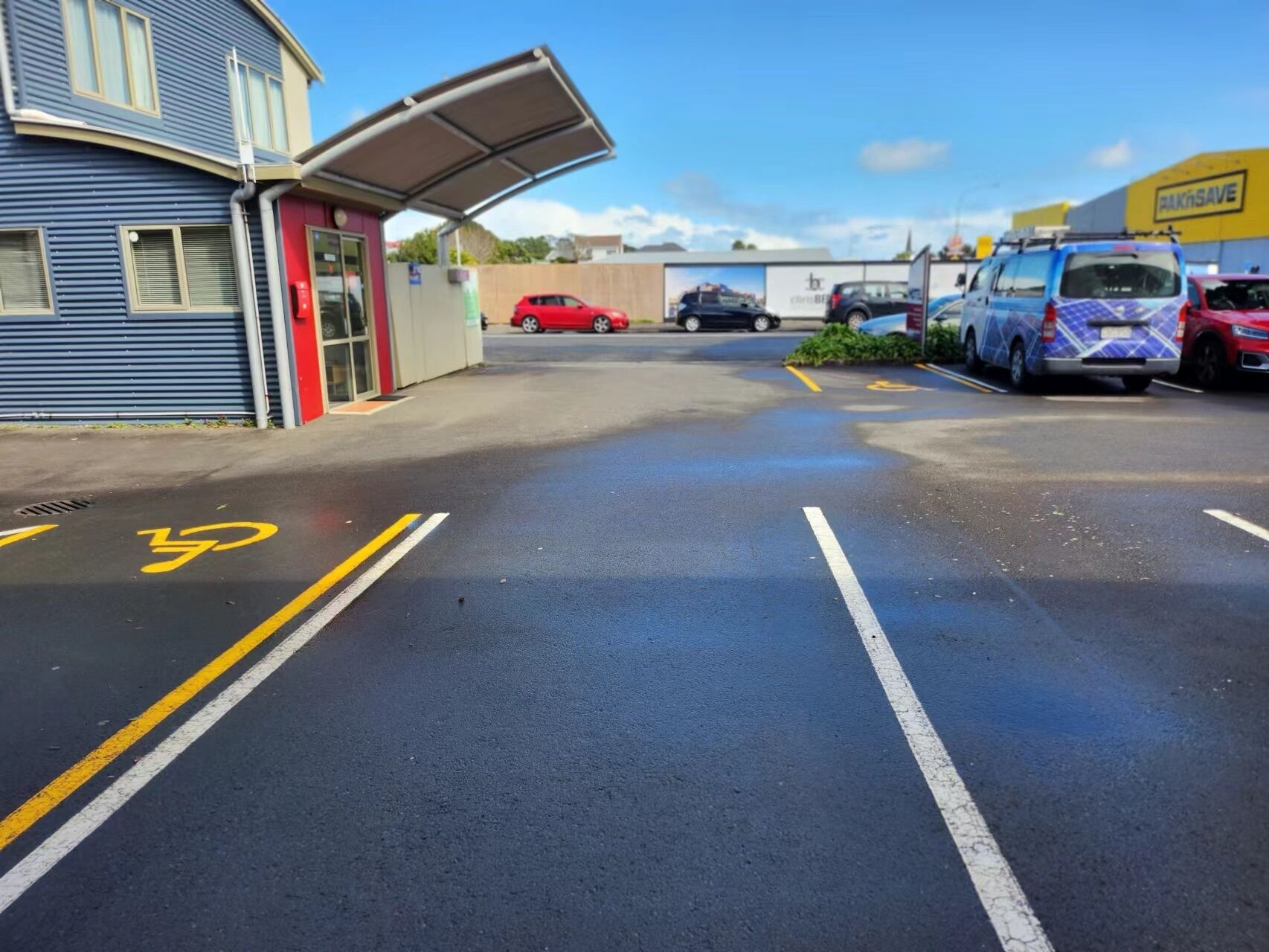 Ein Parkplatz mit eingezeichneten Radwegen und ein Gebäude mit einer roten Tür.