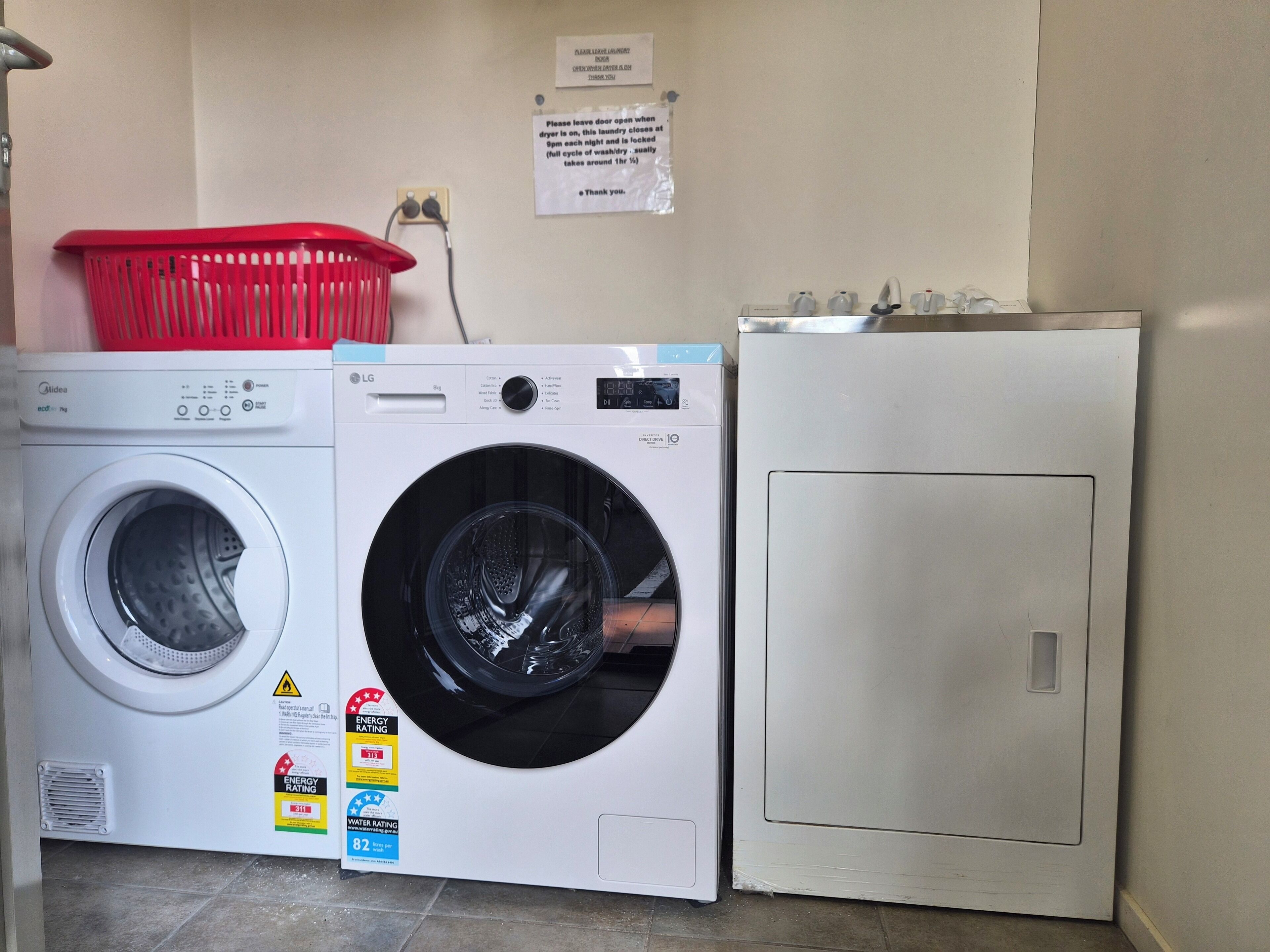 A laundry area with a front-loading washing machine, a top-loading dryer, and a stacked washer-dryer unit.