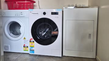 A laundry area with a front-loading washing machine, a top-loading dryer, and a stacked washer-dryer unit.