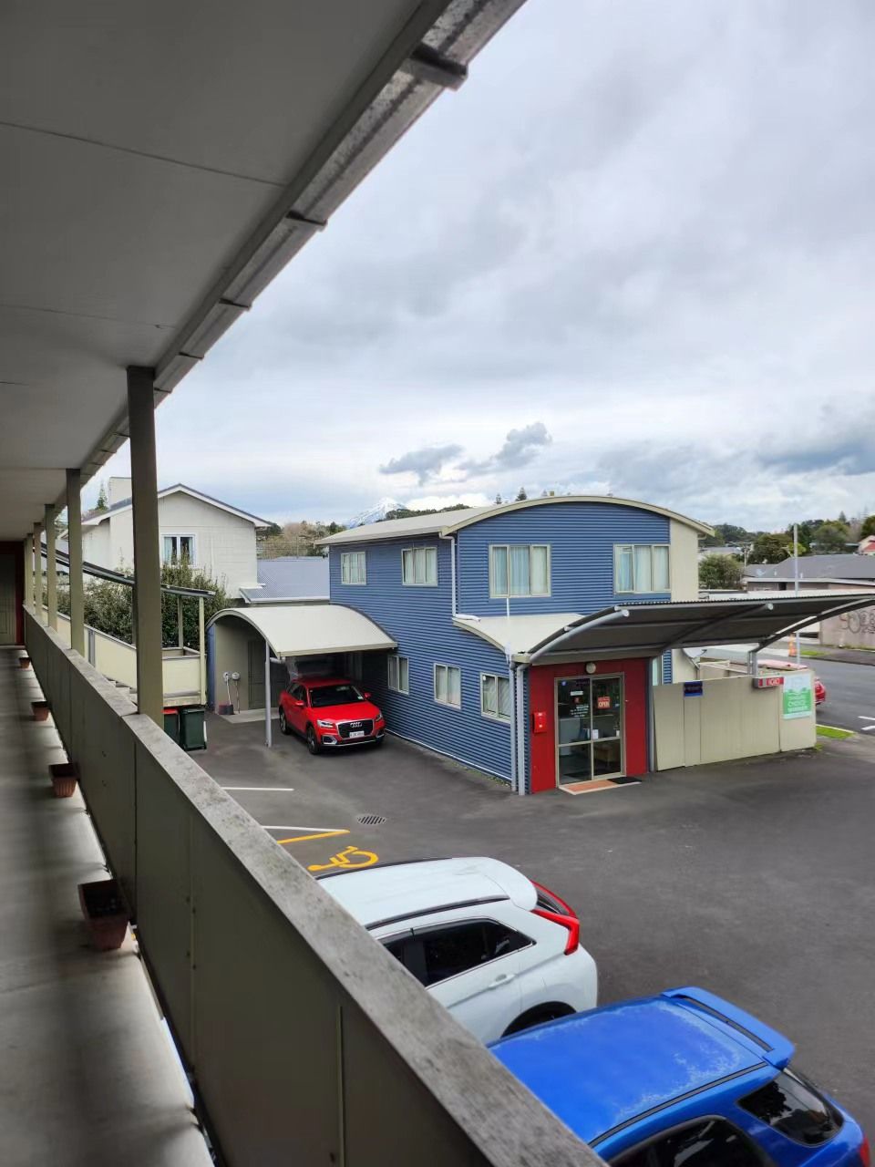 A gas station with a blue building, a red car, and a white car parked.