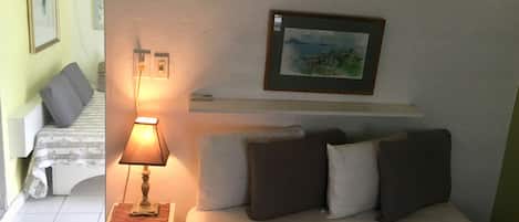 Una habitación de hotel con cama, mesita de noche, lámpara y un cuadro en la pared.