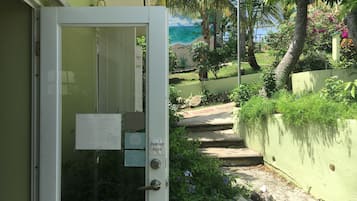 Una puerta con sistema de empuje, un muro verde y un sendero que lleva a una playa.