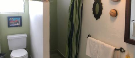 A bathroom with a toilet, shower curtain, and a sink with a mirror.