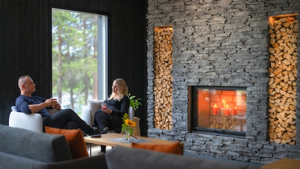 Ein modernes Wohnzimmer mit Kamin aus Stein, gemütlicher Sitzgelegenheit und großem Fenster.