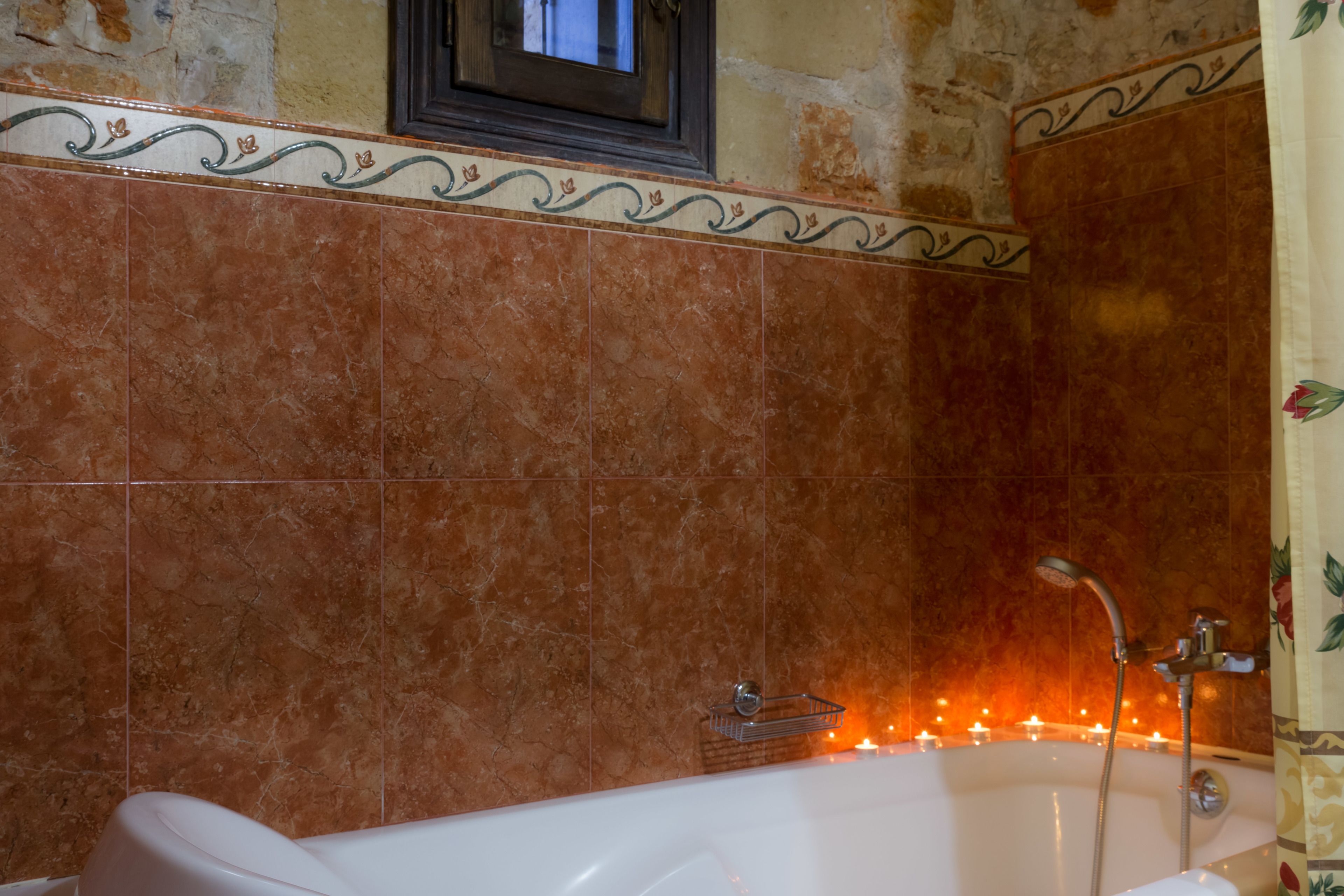 A bathroom with a bathtub, tiled walls, and a shower.