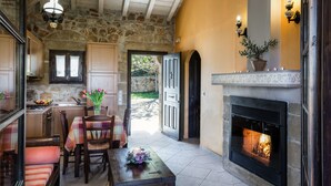 Un interior acogedor con una pared de piedra, una chimenea y un comedor con mesa y sillas.