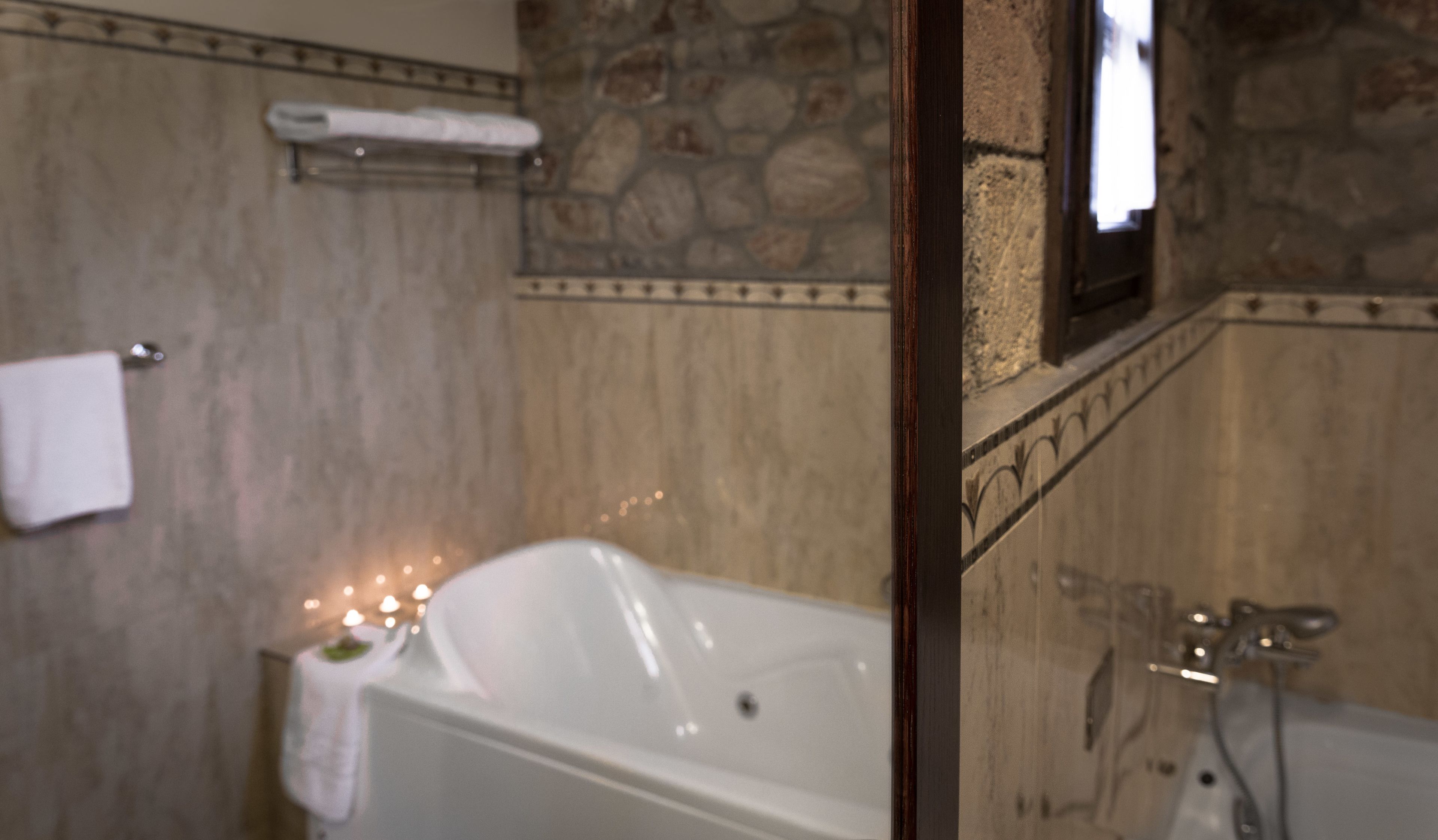A bathroom with a bathtub, a shower, and a stone wall.