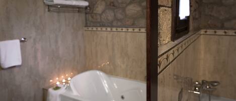 A bathroom with a bathtub, a shower, and a stone wall.