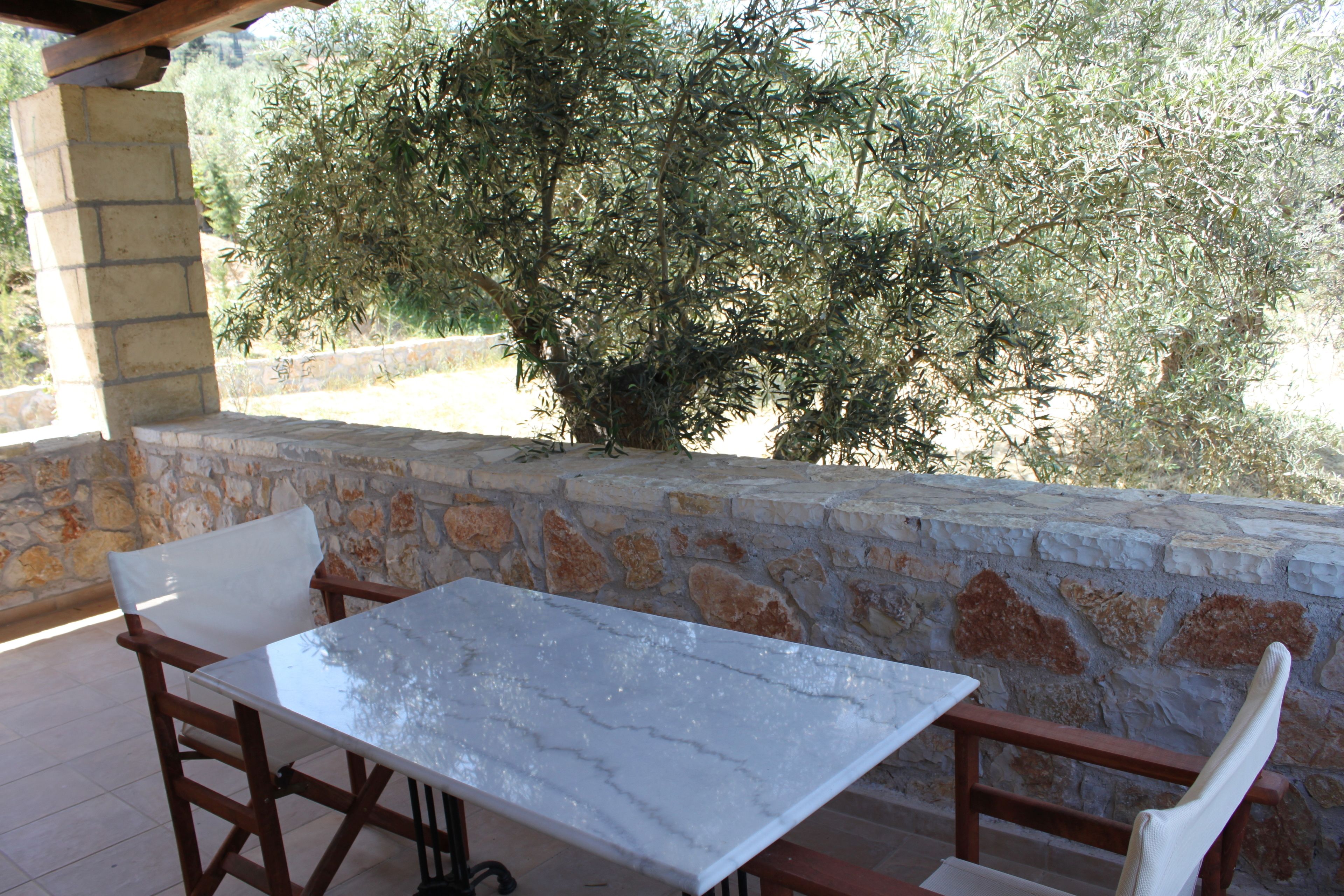 Un patio al aire libre con pared de piedra, una mesa y sillas.