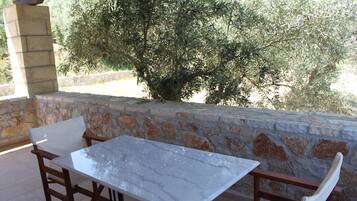 Un patio al aire libre con pared de piedra, una mesa y sillas.