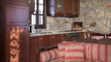 A cozy kitchen with wooden cabinets, a stone wall, and a dining area with a sofa and chairs.