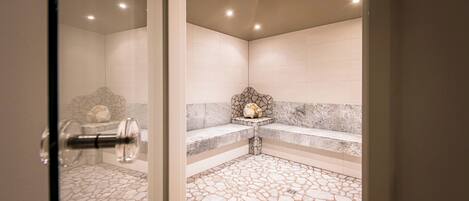 Un baño moderno con piso de piedra, un banco y un detalle decorativo en la pared.