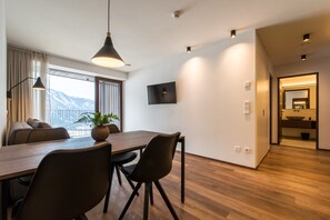 A modern dining area with a wooden table, black chairs, and a hanging pendant light. - Mountain Residence Montana (Valle di Casies)