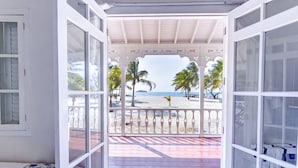Ein Zimmer mit Blick auf einen Strand, ein Balkon mit Geländer und ein Musterparkettboden.