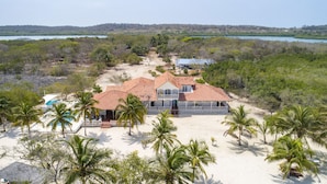Ein großzügiges, zweistöckiges Strandhaus mit rotem Ziegeldach, mehreren Balkonen und einem Swimmingpool.