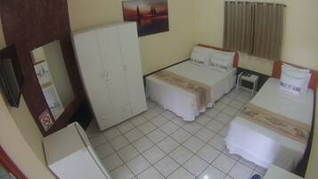 A hotel room with two beds, a wardrobe, a mirror, a flat-screen TV, and a ceiling fan.