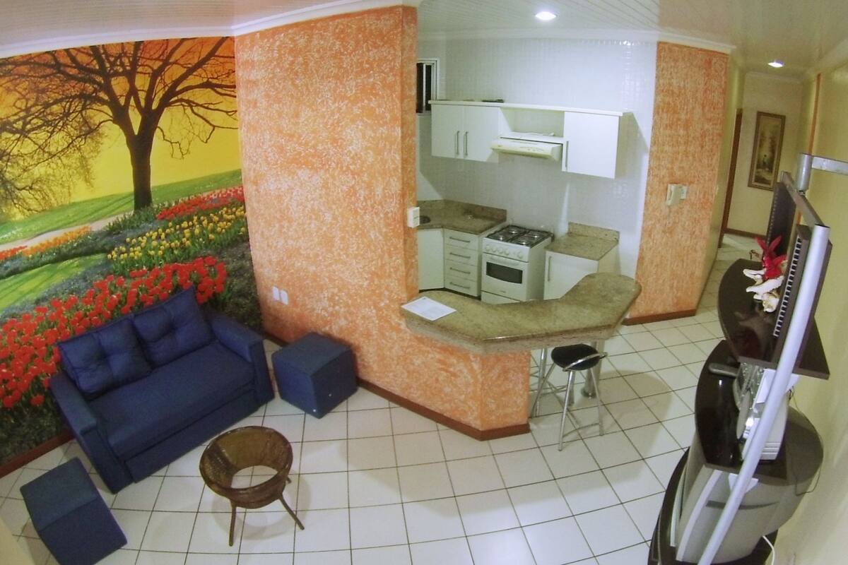 A compact living space with a kitchenette, a blue sofa, and a small dining area.