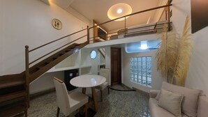 A spacious living area with a high ceiling, a staircase, a round dining table, and a sofa. - Hotel Riviera D'Amazonia (Ananindeua)