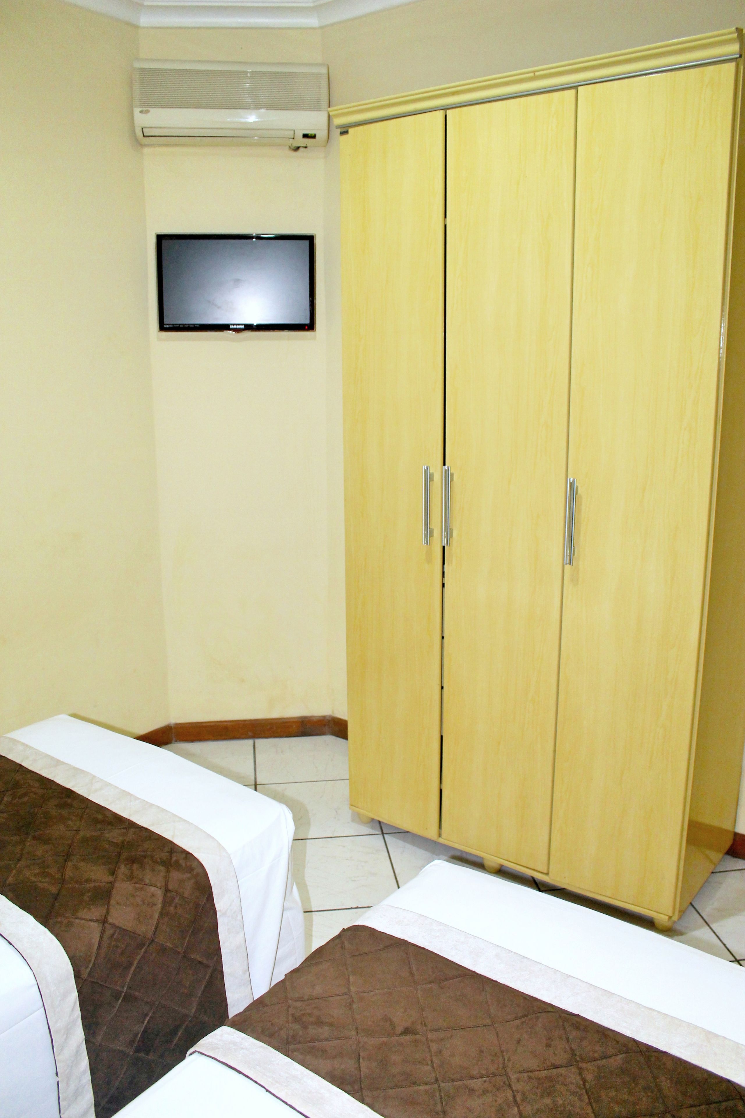 Una habitación con dos camas, un armario y una televisión de pantalla plana.