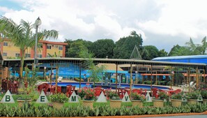 A resort with outdoor seating, a pool, and a building with a mural.