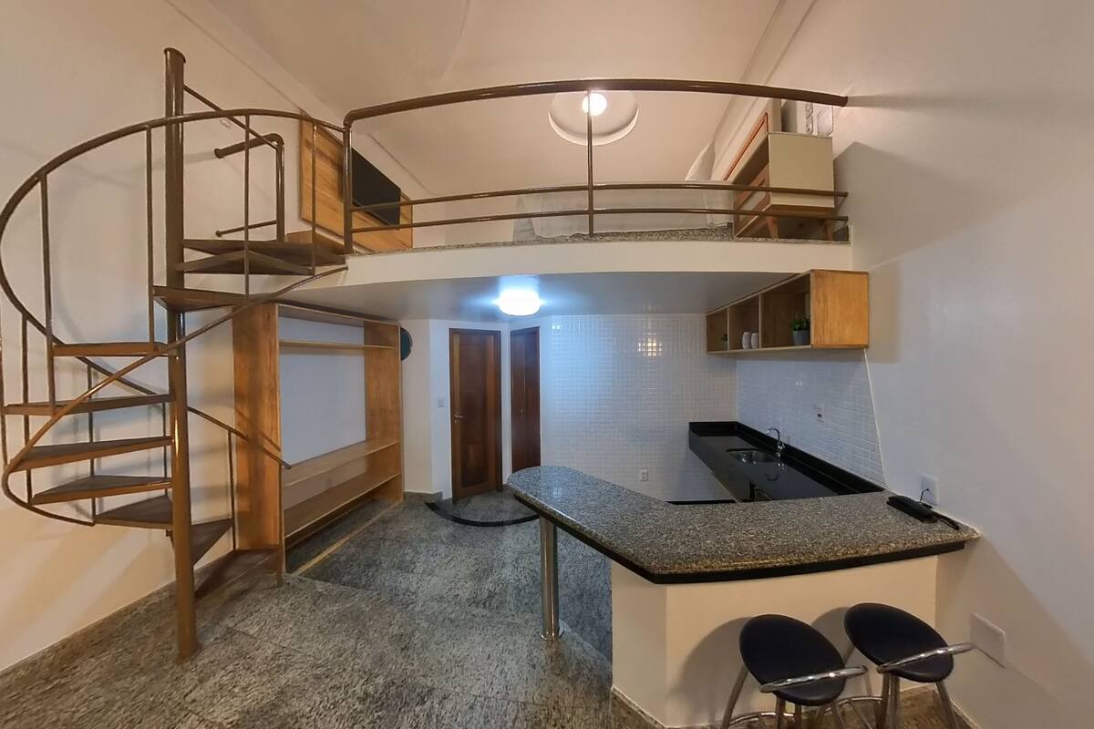 A compact kitchen with a central island, a spiral staircase, and a small seating area.
