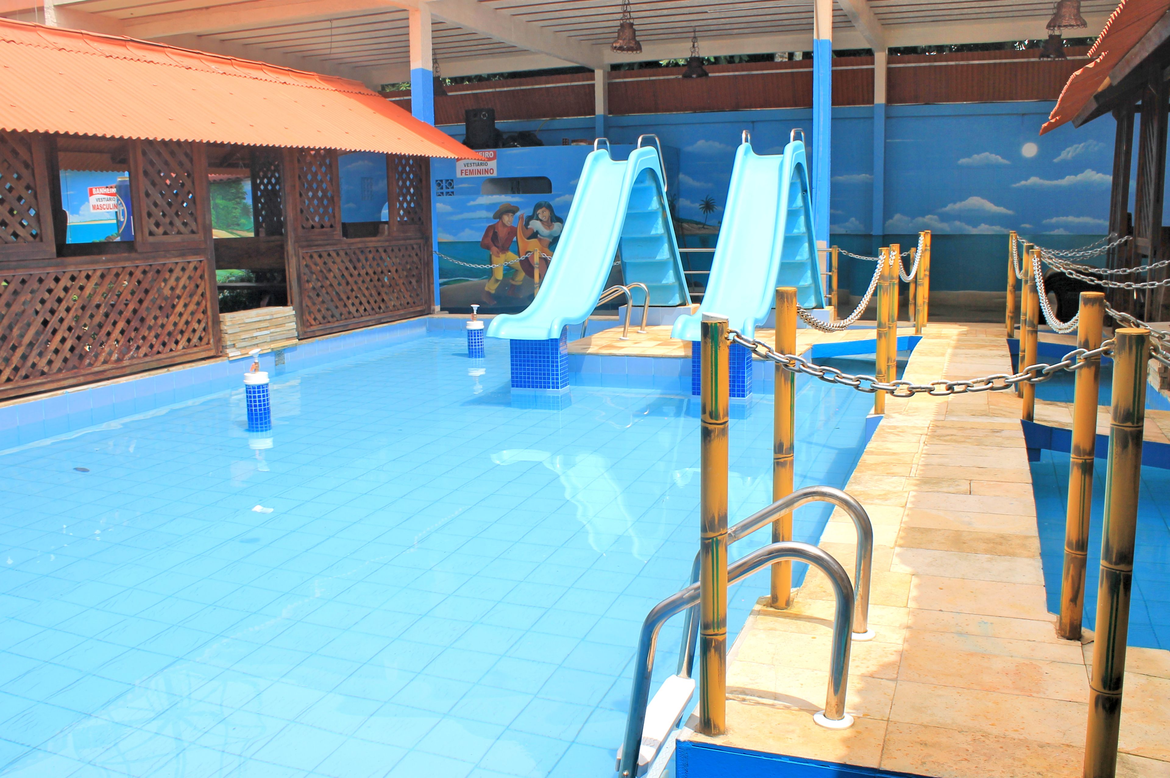 Piscina com duas escorregas e área de deck de madeira.