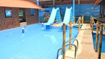 Piscina com duas escorregas e área de deck de madeira.