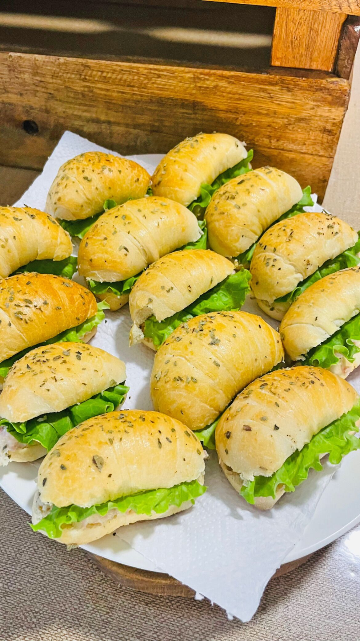 A tray of sandwiches with bread rolls and lettuce.