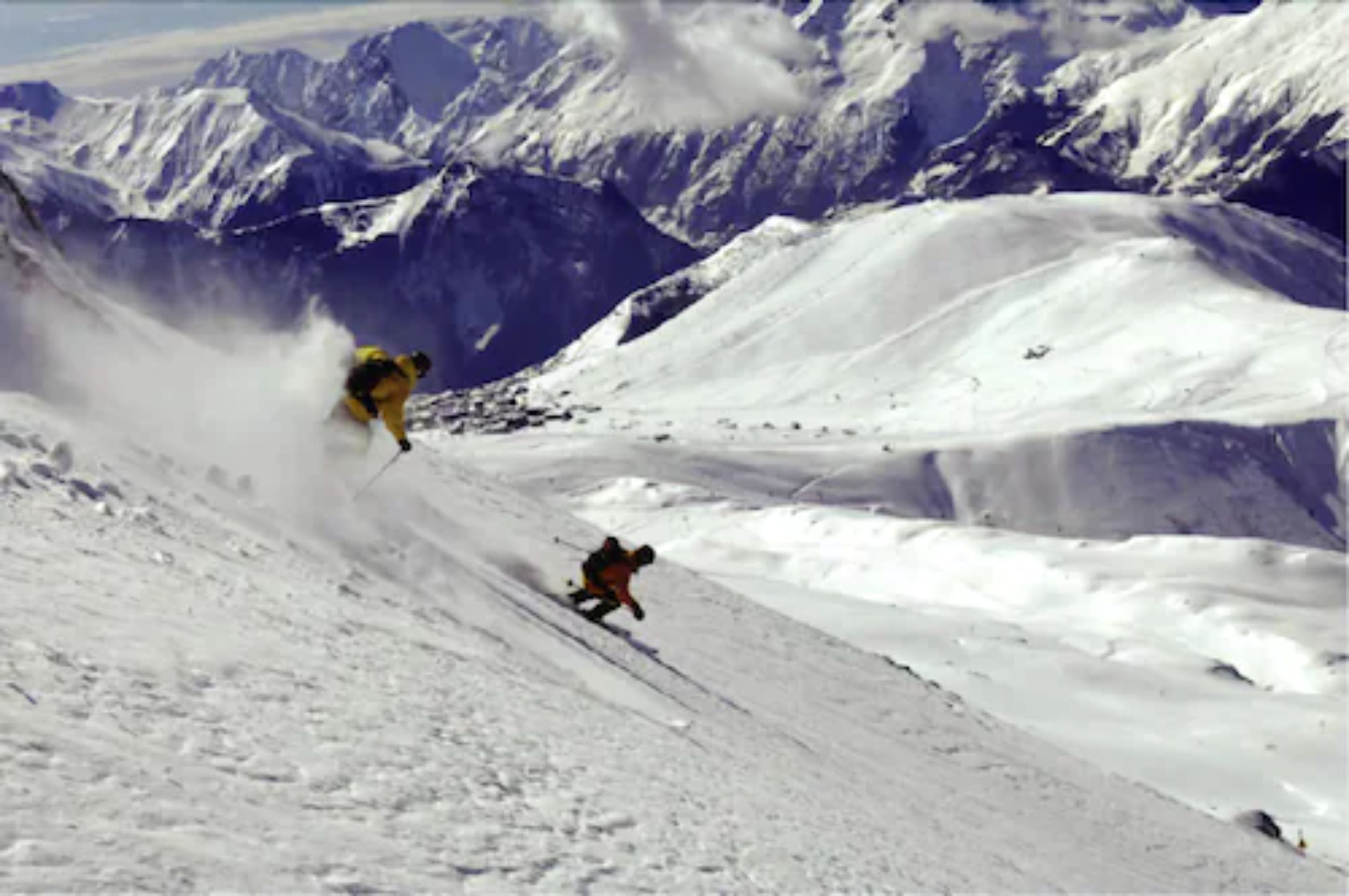 A snowy mountain slope with a person skiing down.