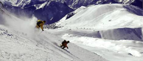 A snowy mountain slope with a person skiing down.