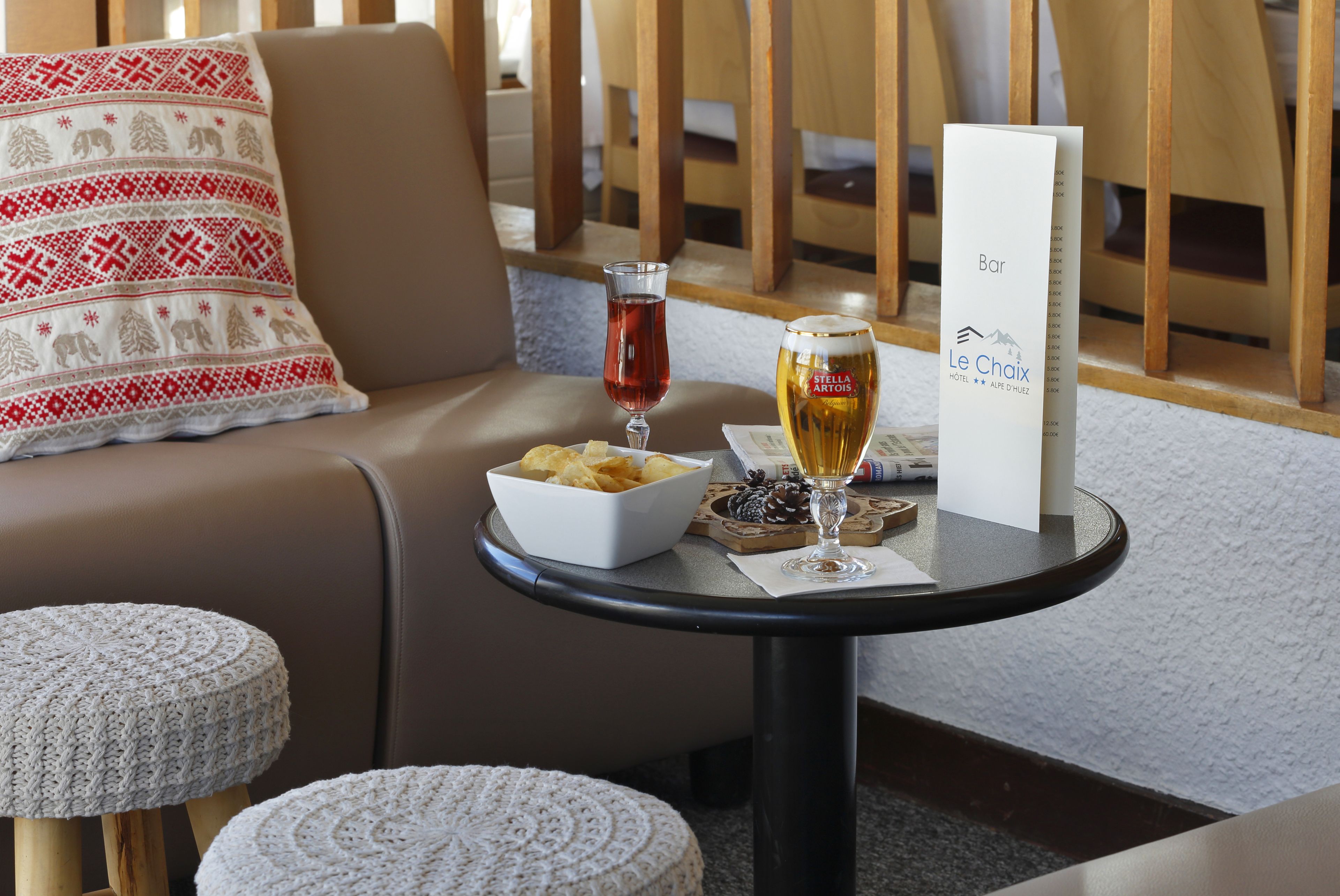 Et hyggeligt opholdsområde med en polstret sofa, et lille rundt bord med snacks, et glas rødvin og et glas øl.