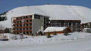 A multi-story hotel with a ski slope in the background.