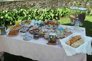 Un buffet en plein air proposant une variété de plats et de boissons, le tout installé devant un mur en pierre.