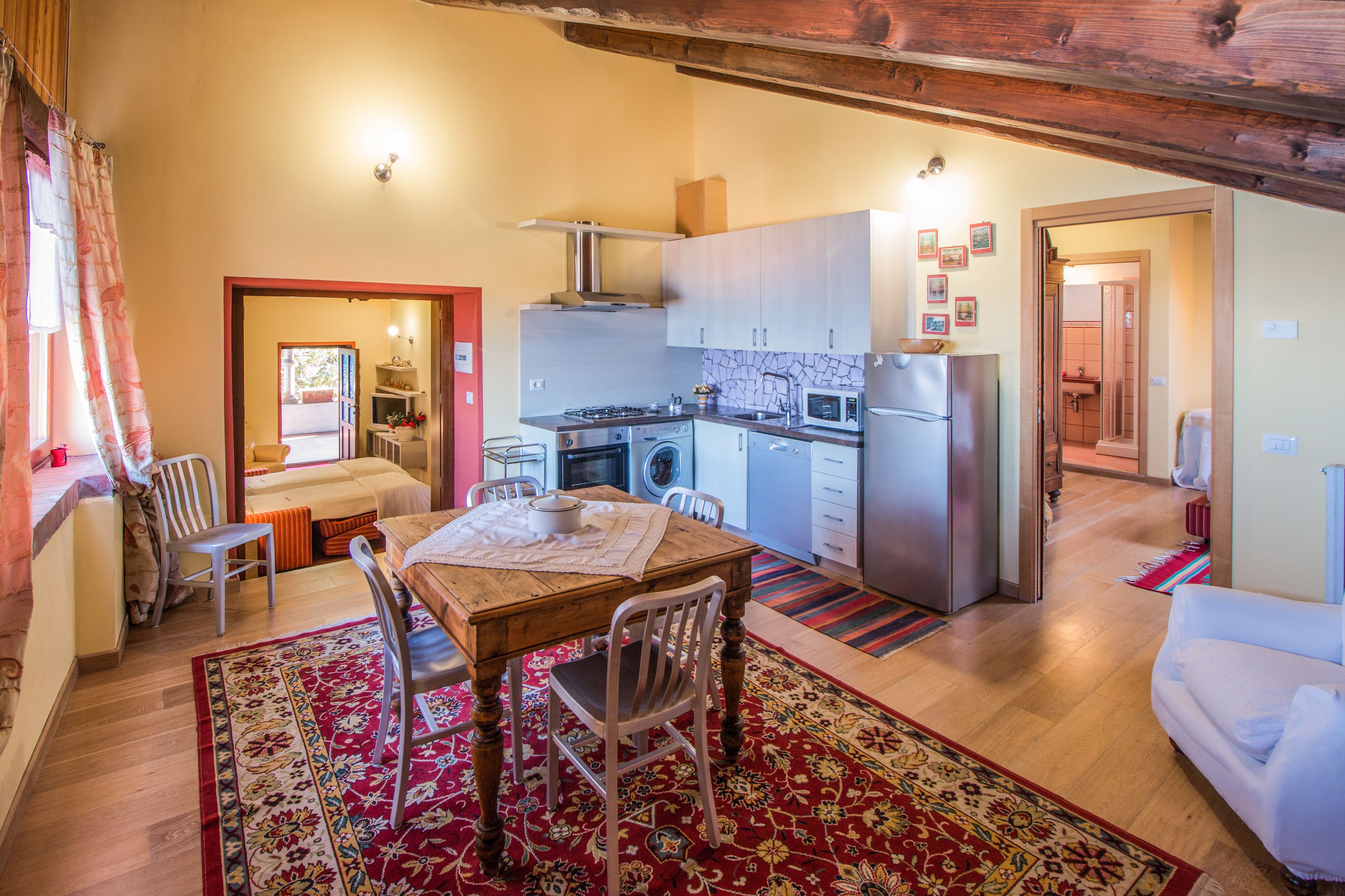 A compact kitchen with modern appliances, a dining area with a wooden table and chairs, and a living area with a sofa.