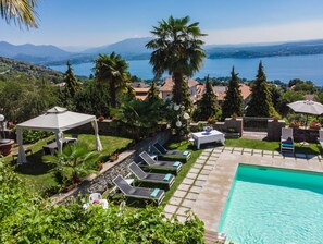 Un espace piscine aménagé avec des chaises longues, une table et une pergola.