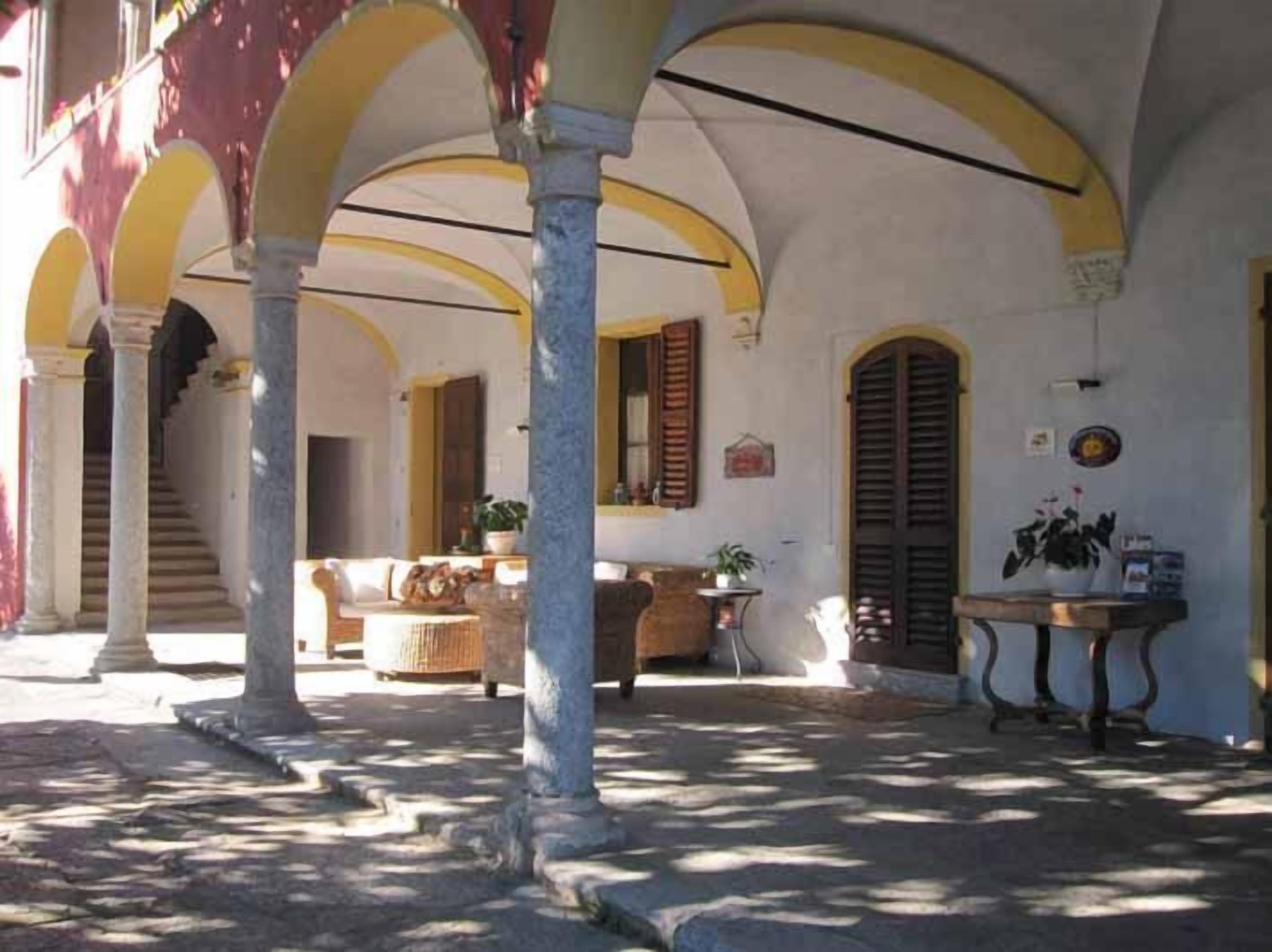 Une cour intérieure couverte, agrémentée d’arches, de colonnes et d’un escalier menant à un niveau supérieur.